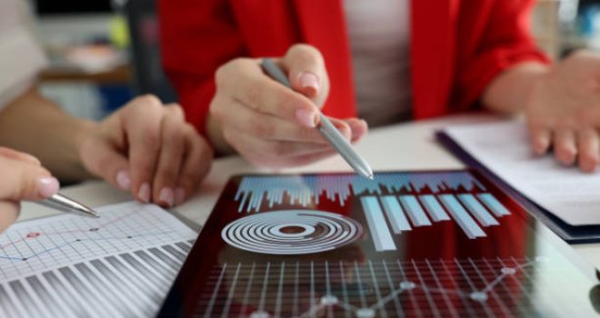 istockphoto-1299055072-612×612 Business women studying charts and diagrams on digital tablet closeup. Business meetings concept